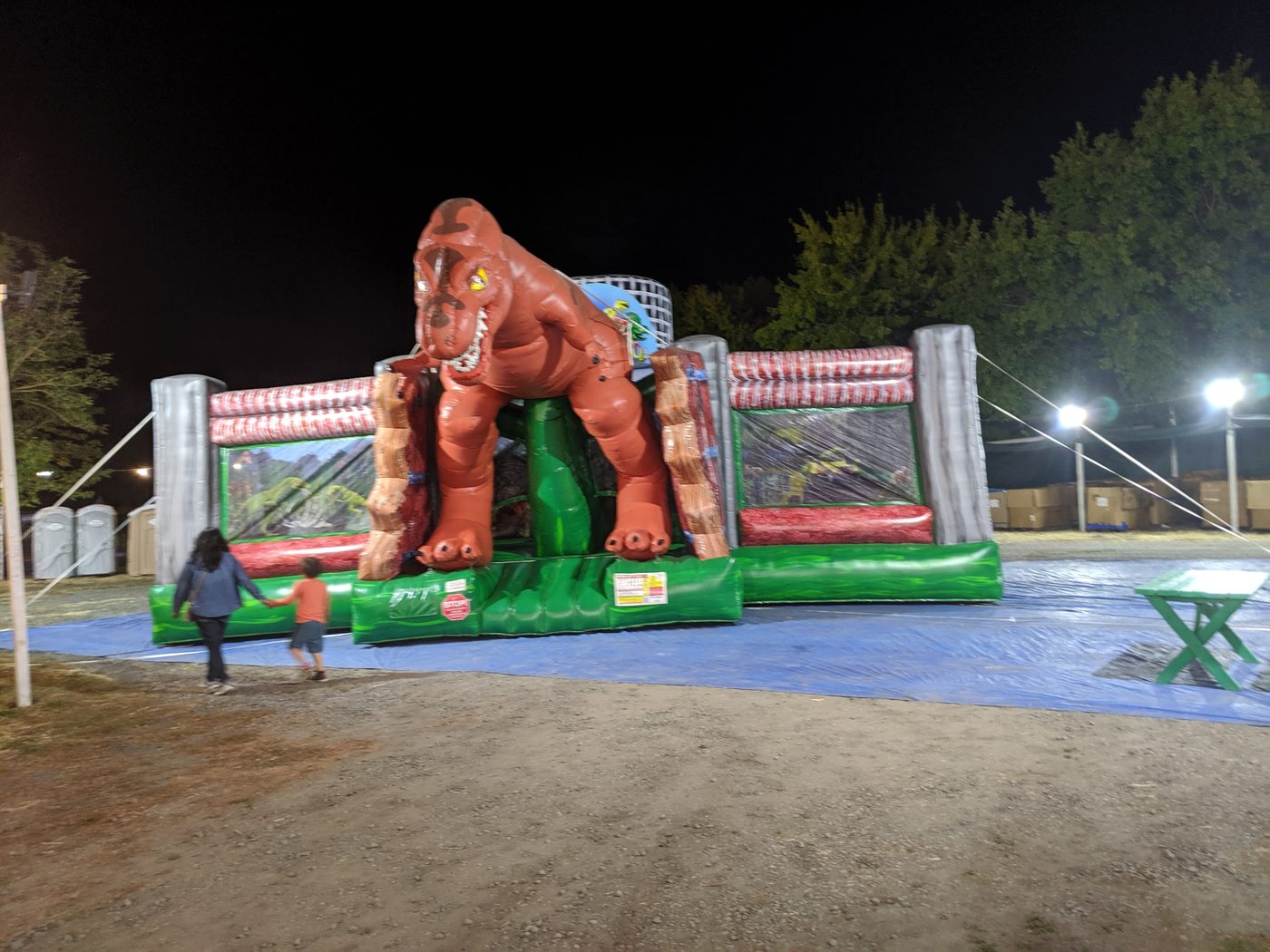 T-Rex jump house lit up at night at the patch